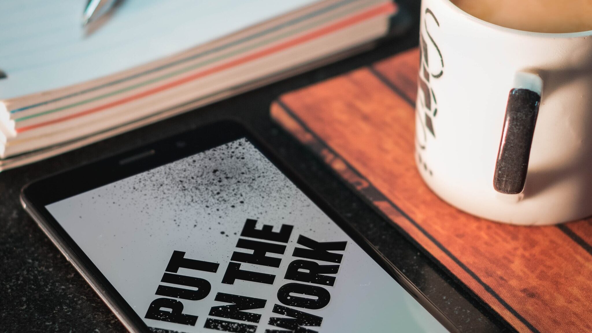 Honor smartphone beside mug and paper with pen